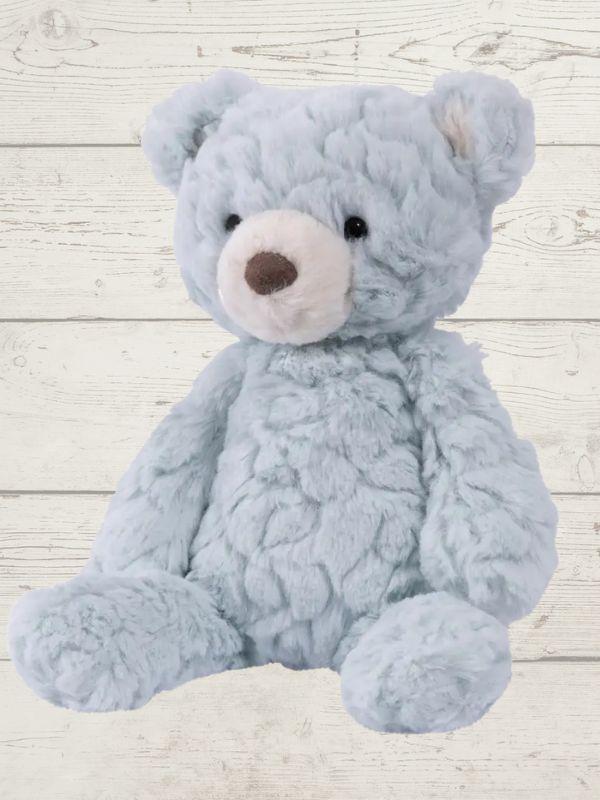 a blue bear sitting on a wooden surface 