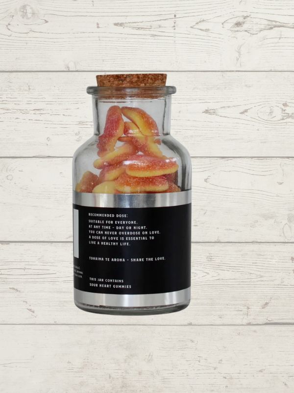 Jar of gummy worms with a cork lid on a wooden surface