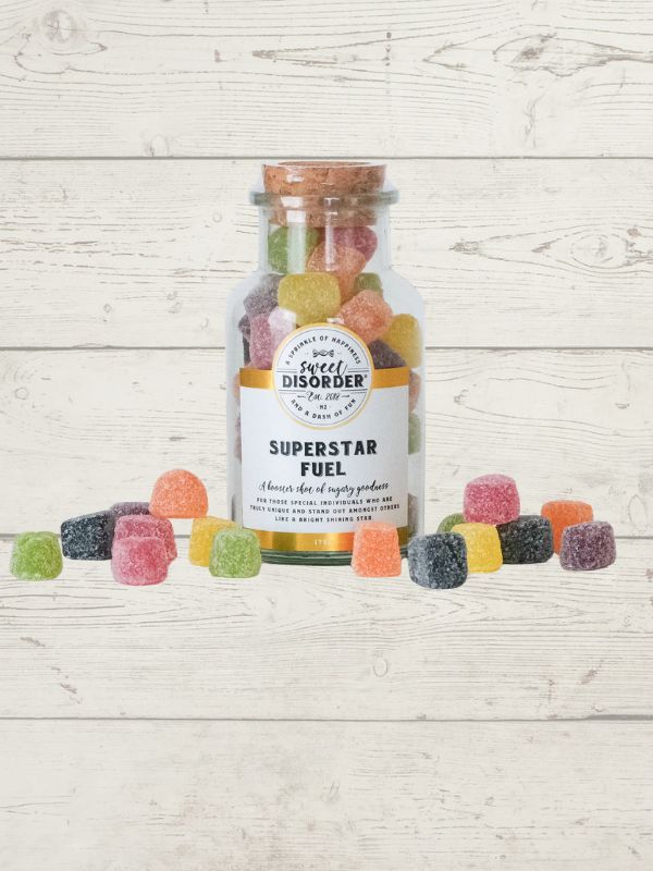 Bottle of 'Superstar Fuel' gummy bears with a label on a wooden surface