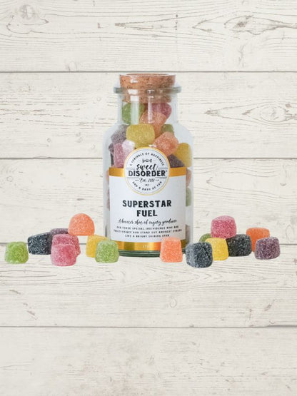 Bottle of 'Superstar Fuel' gummy bears with a label on a wooden surface