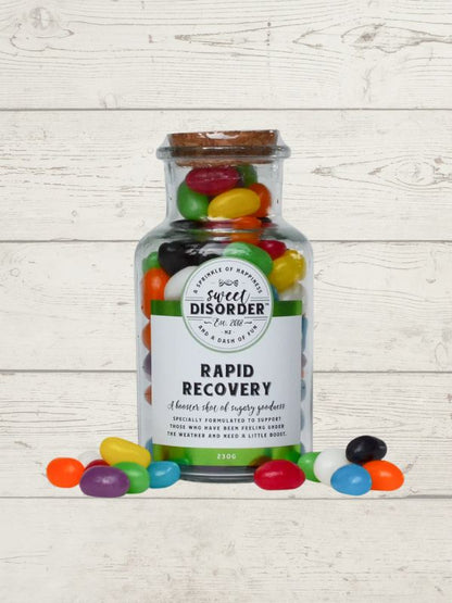 Jar of jelly beans with a label reading 'Sweet Disorder' on a wooden surface.