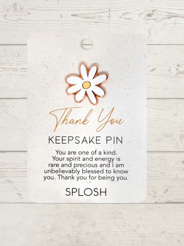 A keepsake pin with a floral design, predominantly in a rose gold color, attached to a card with a 'Thank You' message.