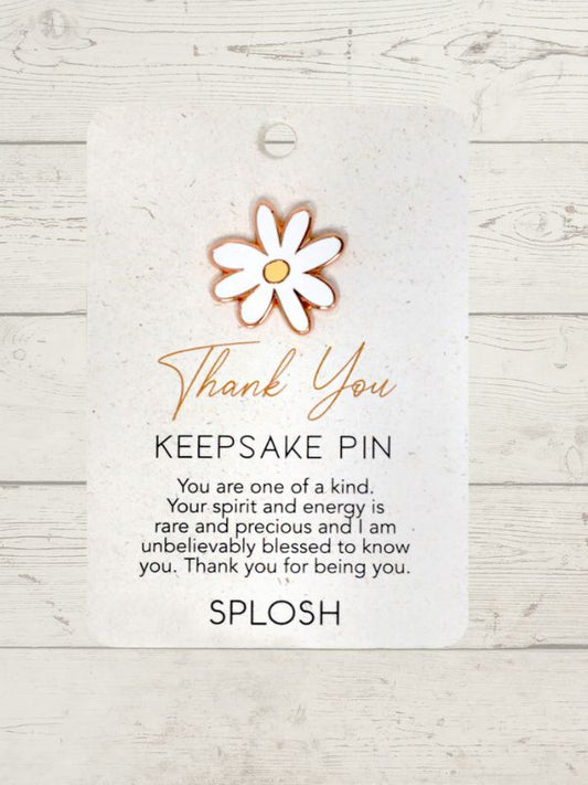 A keepsake pin with a floral design, predominantly in a rose gold color, attached to a card with a 'Thank You' message.