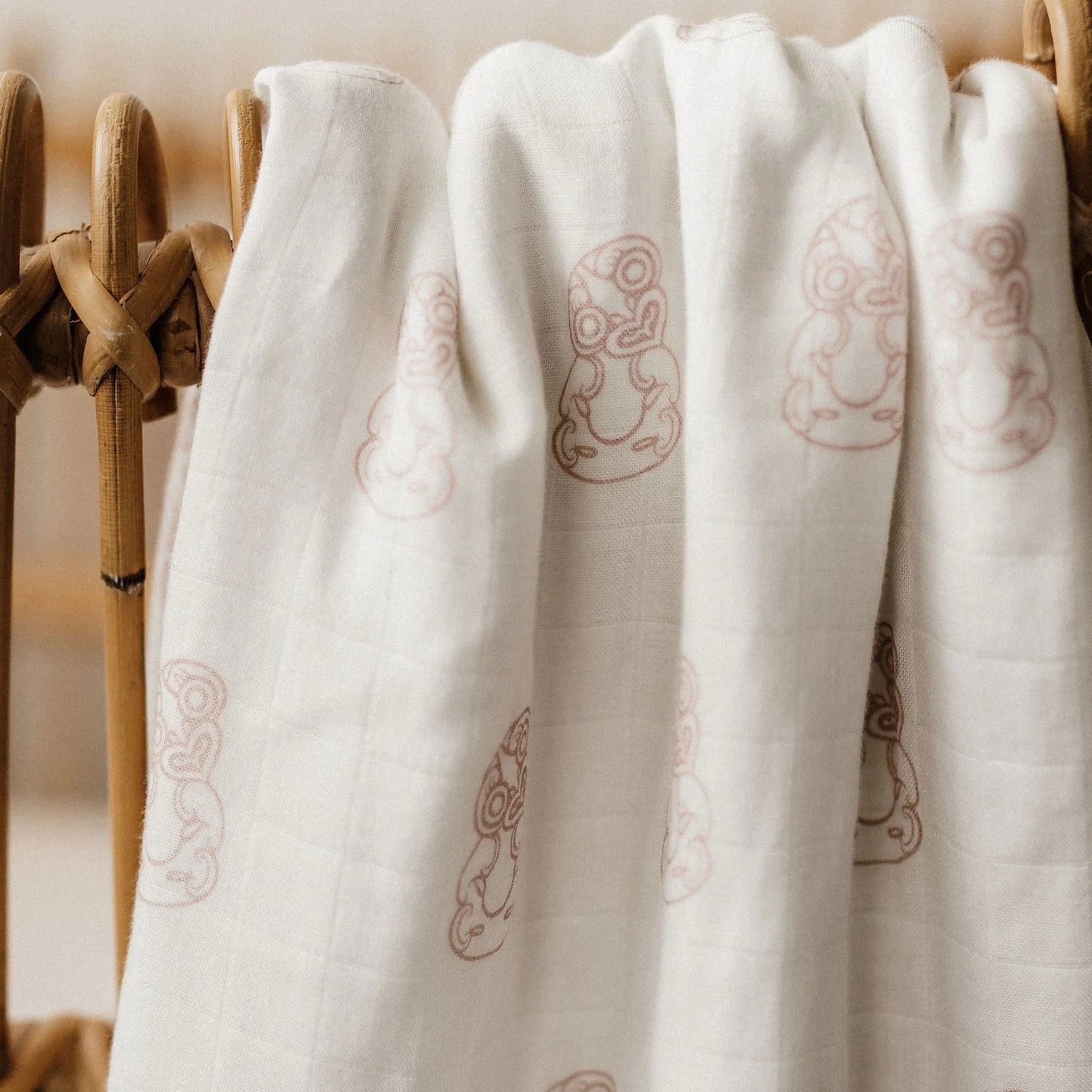 White fabric with embroidered patterns draped over a wooden basket.