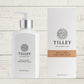 A collection of Tilley branded room spray bottles displayed against a wooden background. The bottles are varied in size and design, with a consistent white and silver label design featuring the Tilley logo.