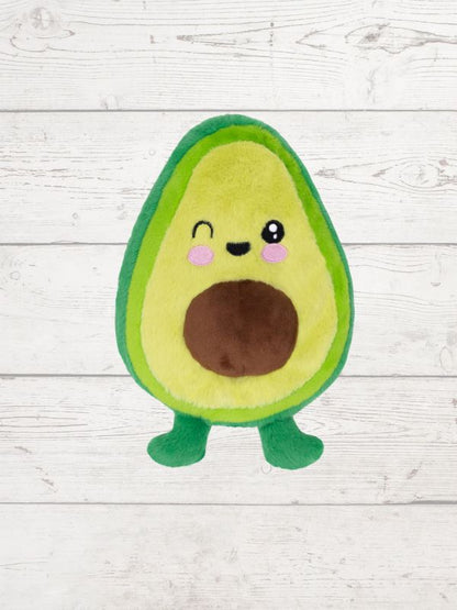 Plush avocado toy with a smiling face on a wooden surface
