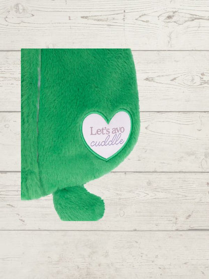 Green plush toy with a heart-shaped patch on a wooden surface