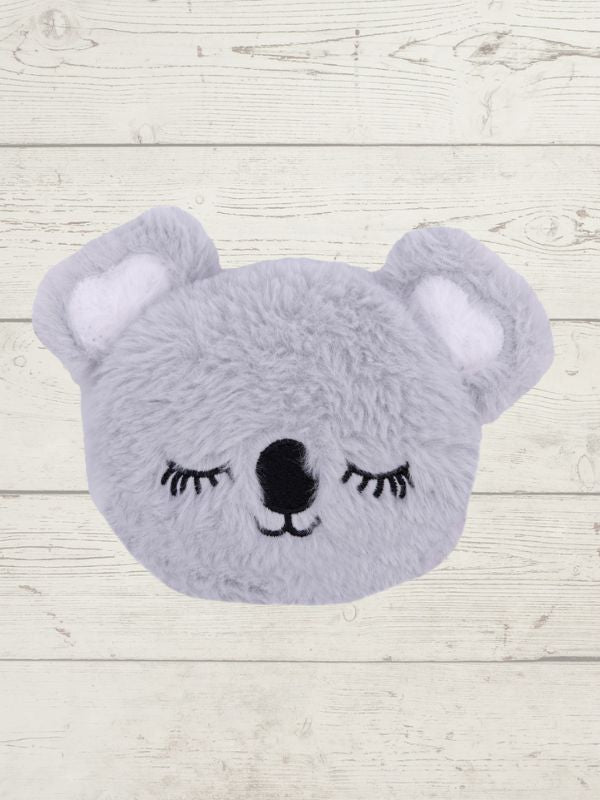 Gray plush toy shaped like a bear with closed eyes on a light wooden background