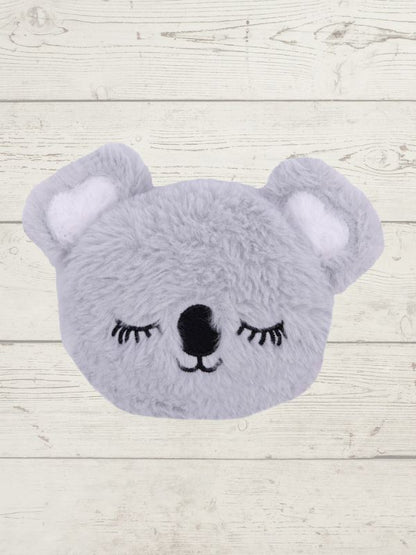 Gray plush toy shaped like a bear with closed eyes on a light wooden background