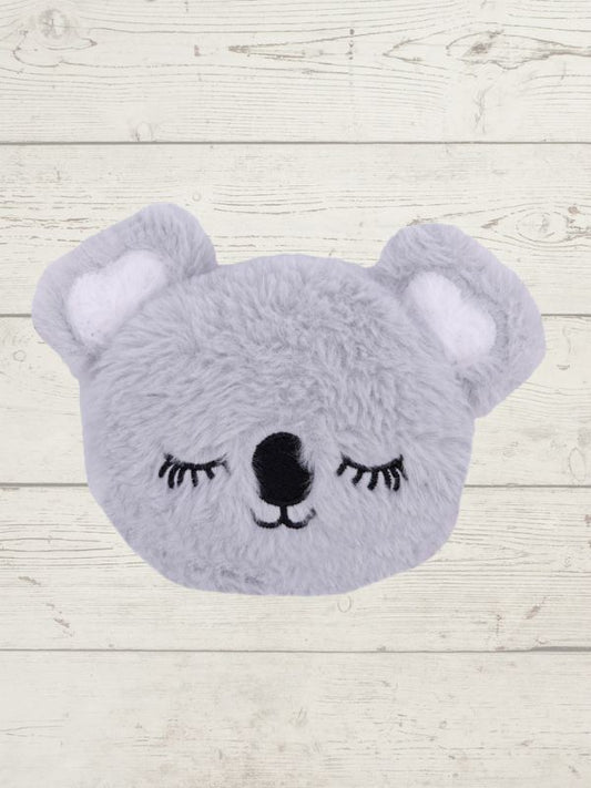 Gray plush toy shaped like a bear with closed eyes on a light wooden background