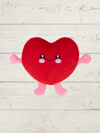 Red heart-shaped plush toy with a smiling face on a light wooden surface