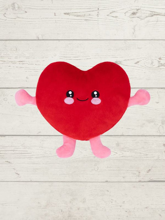 Red heart-shaped plush toy with a smiling face on a light wooden surface