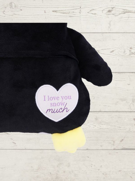 Black penguin plush toy with a heart-shaped tag on a wooden surface