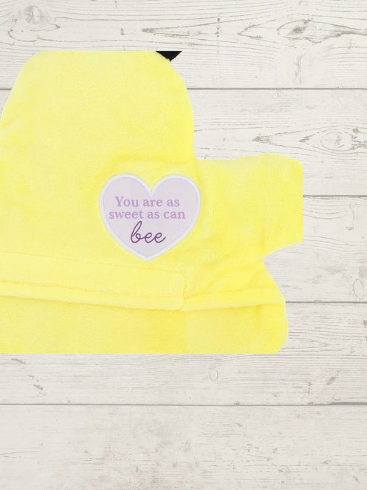 Yellow hooded towel with a heart-shaped sticker on a wooden surface