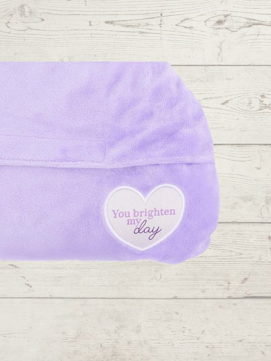 Purple towel with a heart-shaped message on a wooden surface