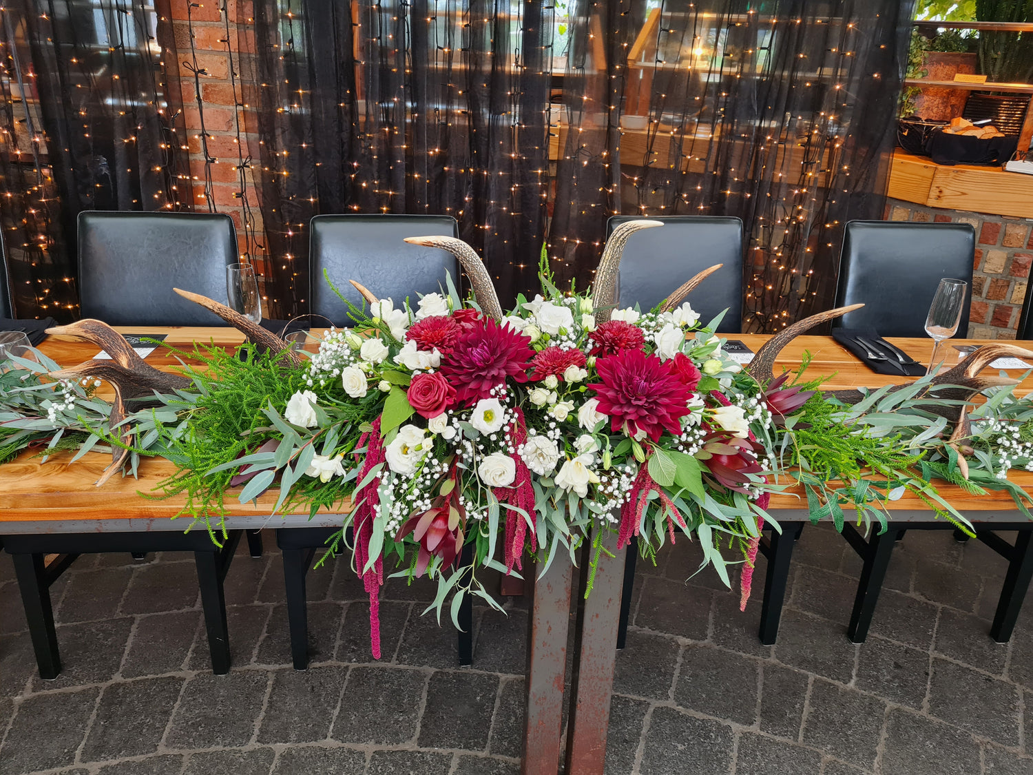 Decorative table setup with floral arrangements and chairs in a cozy indoor setting.