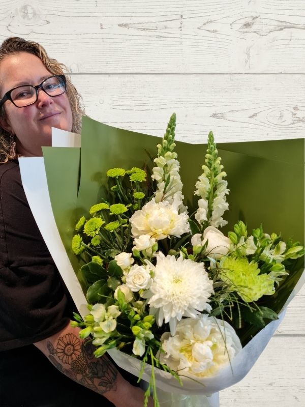 A person holding a white and green palette bouquet of flowers.