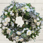 A white and green Sympathy wreath with a mix of white and green flowers, designed to be held in a hand.