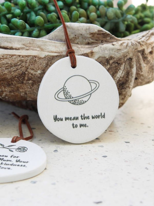 Two round ceramic plaques with embossed text and a world map design, one with a rope for hanging.
